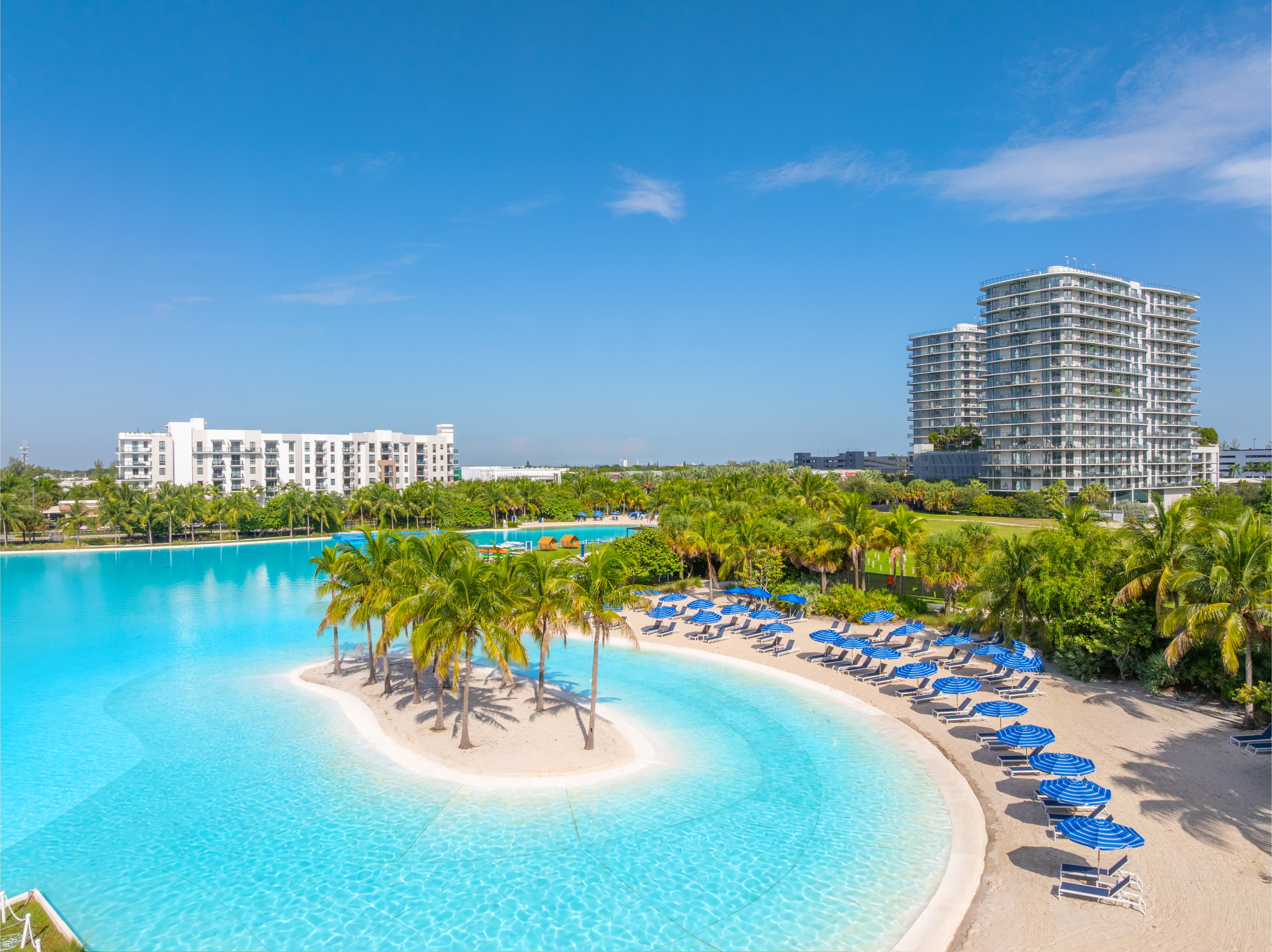 A large swimming pool with a small island in the middle and palm trees around it.